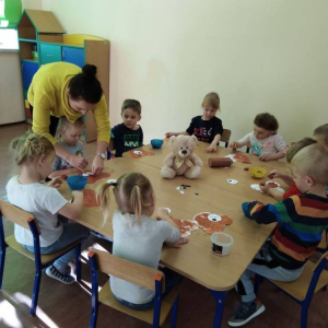 Dzieci podczas zajęć plastycznych - na stole stoi Miś